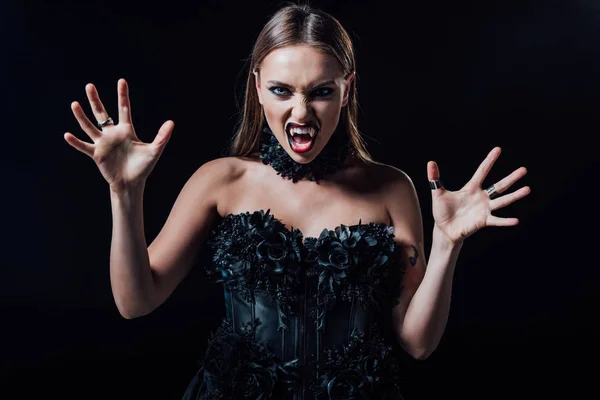 Scary vampire girl with fangs in black gothic dress isolated on black — Stock Photo