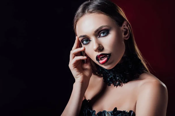 Assustador vampiro menina com presas em preto vestido gótico no fundo preto — Fotografia de Stock