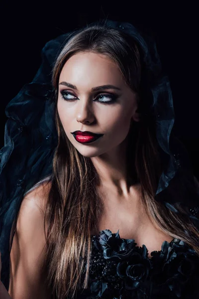 Scary vampire girl in black gothic dress and veil looking away isolated on black — Stock Photo