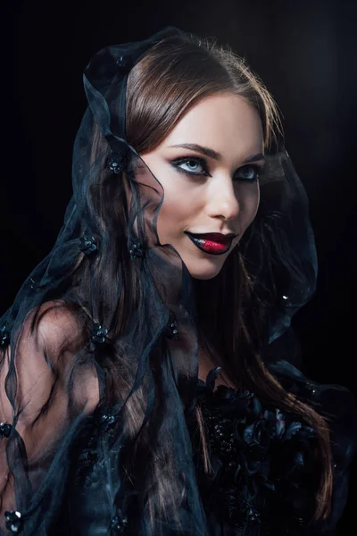 Sorridente ragazza vampiro spaventoso in abito gotico nero e velo isolato su nero — Foto stock