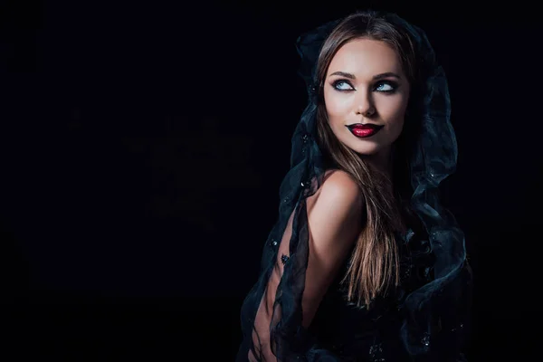 Scary vampire girl in black gothic dress and veil looking away isolated on black — Stock Photo