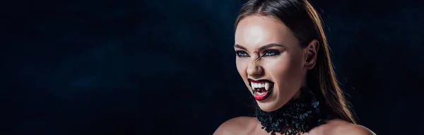 Panoramic shot of scary vampire girl with fangs in black gothic dress isolated on black — Stock Photo