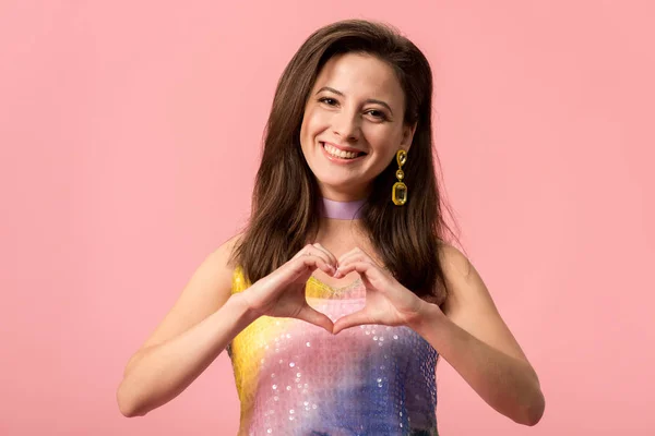 Happy young stylish disco girl showing heart gesture isolated on pink — Stock Photo