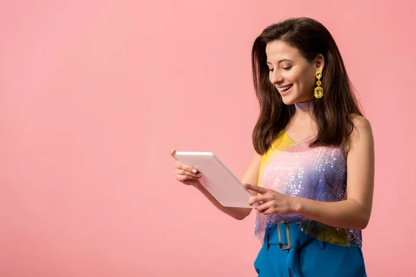 Sorridente giovane ragazza discoteca elegante tenendo tablet digitale isolato su rosa — Foto stock