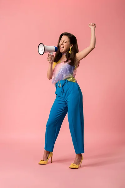 Vista completa de la joven chica disco con estilo gritando en megáfono en rosa - foto de stock
