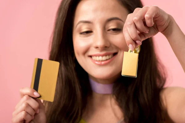 Foco seletivo de menina disco elegante feliz segurando saco de compras e cartão de crédito isolado em rosa — Fotografia de Stock