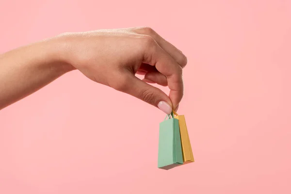 Vista cortada de mulher segurando sacos de compras isolados em rosa — Fotografia de Stock