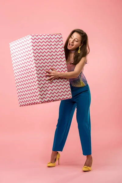 Excité heureux jeune fille disco élégant tenant boîte cadeau sur rose — Photo de stock