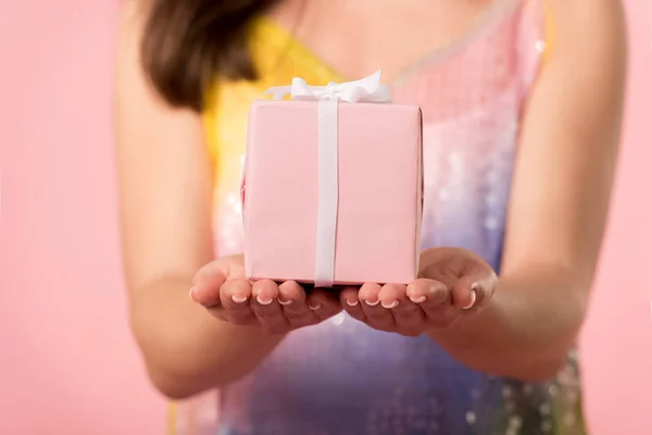 Vista parcial de niña sosteniendo caja de regalo aislado en rosa - foto de stock