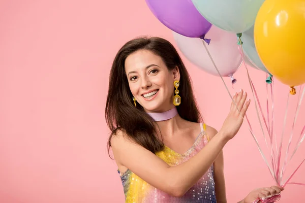 Молода усміхнена вечірка дівчина тримає святкові кульки ізольовані на рожевому — стокове фото