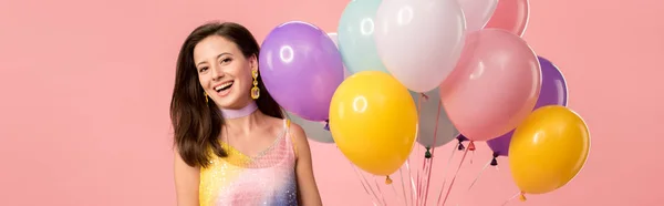 Панорамный снимок молодой улыбающейся девушки с праздничными воздушными шарами, изолированными на розовом — Stock Photo