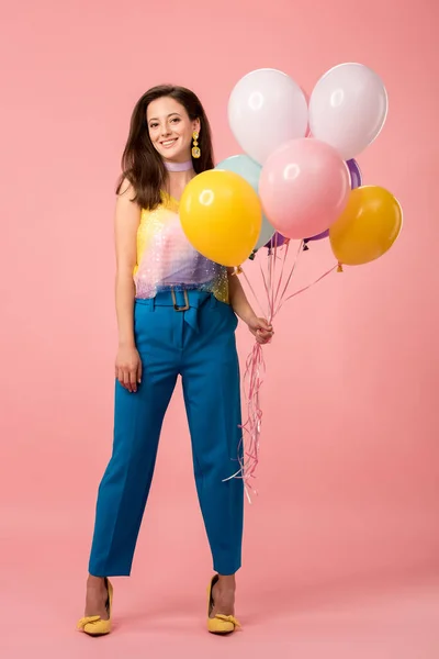 Young happy party girl holding festive balloons on pink — Stock Photo
