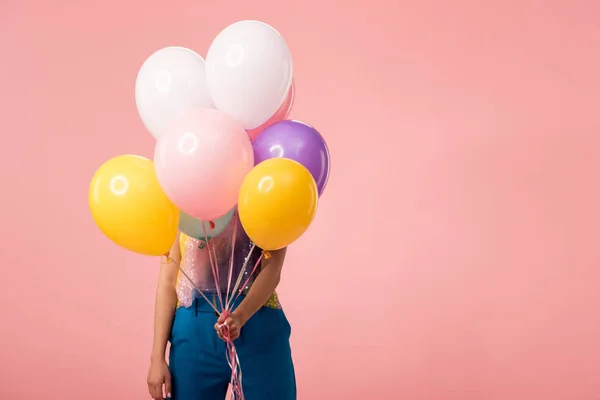 Joven fiesta chica celebración festiva globos en frente de la cara aislado en rosa - foto de stock