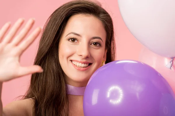 Young happy party girl in festive balloons isolated on pink — Stock Photo