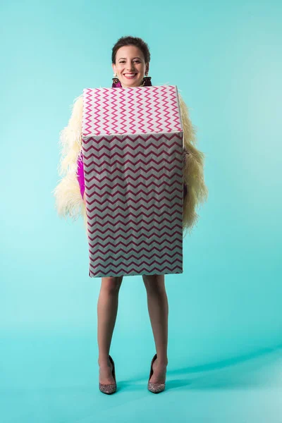 Menina festa feliz em vestido roxo com penas segurando enorme caixa de presente em turquesa — Fotografia de Stock