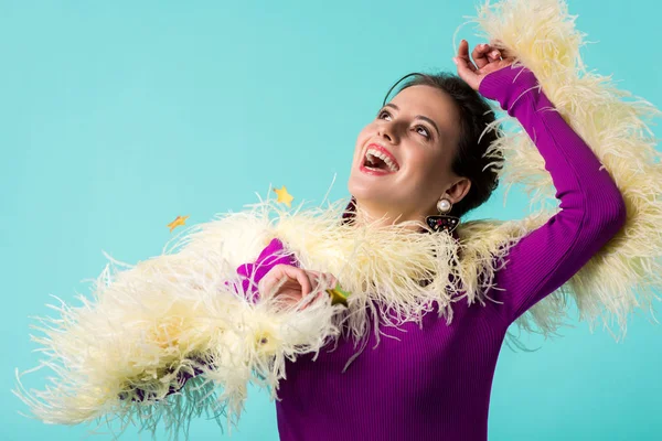 Menina festa feliz em vestido roxo com penas sob queda confete isolado em turquesa — Fotografia de Stock