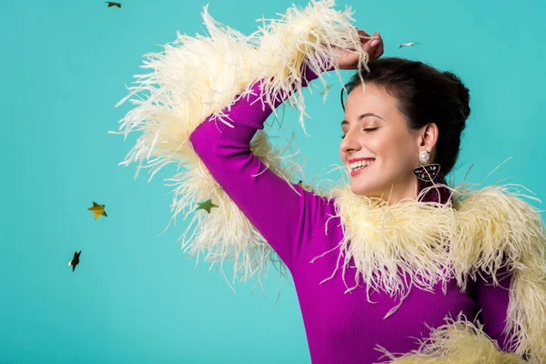 Happy party girl in purple dress with feathers under falling confetti isolated on turquoise — Stock Photo