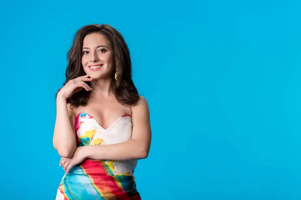 Smiling elegant young woman in dress isolated on blue — Stock Photo