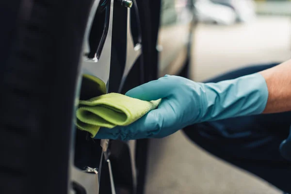 Partial view of car cleaner wiping car wheel with rag — Stock Photo