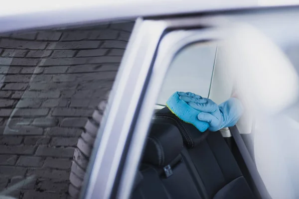 Partial view of car cleaner in rubber glove cleaning car set with sponge — Stock Photo