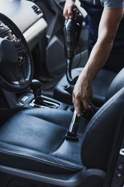 Partial view of car cleaner vacuuming drivers seat in car — Stock Photo