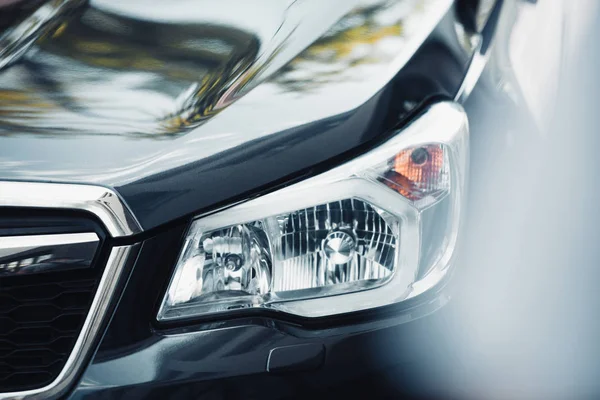 Selective focus of headlamp and capote of black modern car — Stock Photo