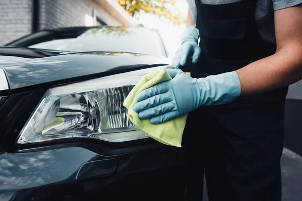 Cropped view of car cleaner wiping headlamp with rag — Stock Photo