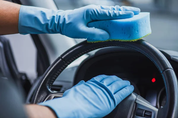 Vista ritagliata del pulitore auto in guanti di gomma pulire volante con spugna — Foto stock