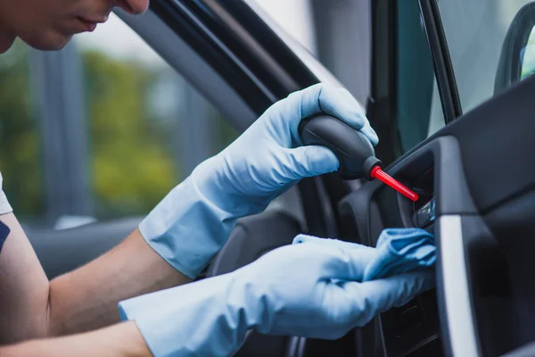 Cropped view of car cleaner dusting dashboard with rubber air blower — Stock Photo