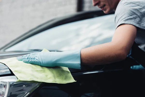 Cropped view of car cleaner wiping car capote with rag — Stock Photo