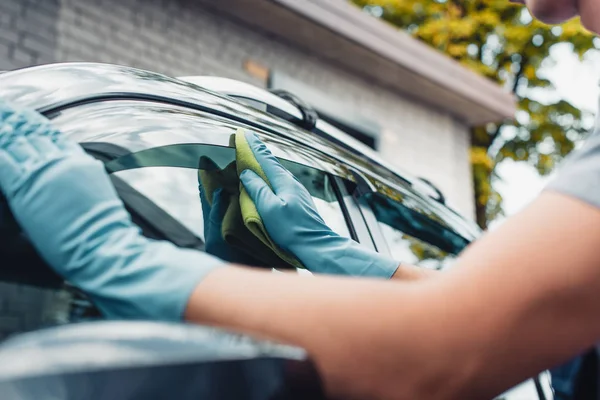 Vue recadrée du nettoyeur de voiture essuyant fenêtre latérale de voiture avec chiffon — Photo de stock