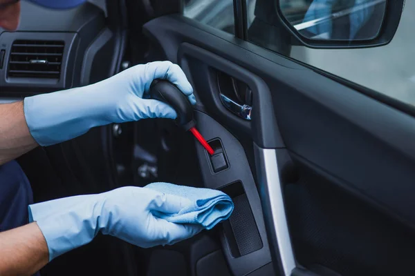 Vista recortada del limpiador de coches desempolvando la puerta del coche con el ventilador de goma - foto de stock