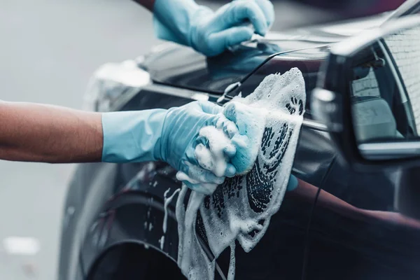 Vista recortada del coche limpiador lavado coche con esponja y detergente - foto de stock