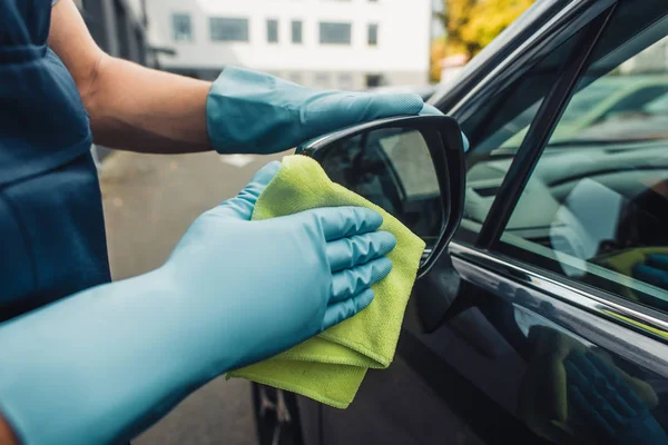 Cropped view of car cleaner wiping side mirror od car with rag — Stock Photo