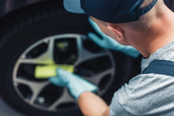 Selective focus of car cleaner wiping wheel with rag — Stock Photo