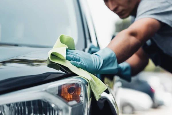 Selective focus of car cleaner wiping capote with rag — Stock Photo