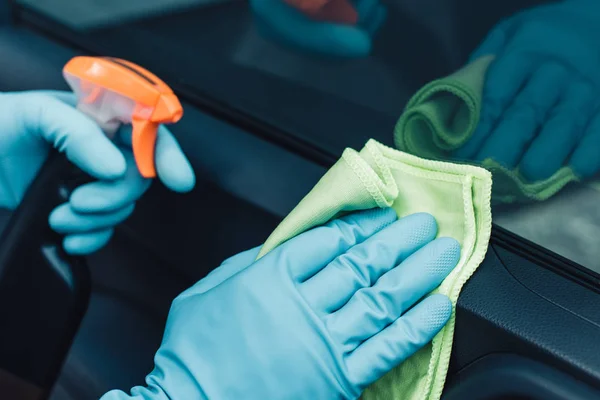 Partial view of car cleaner in rubber gloves cleaning car with rag — Stock Photo