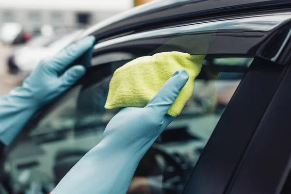 Cropped view of car cleaner wiping door window with rag — Stock Photo