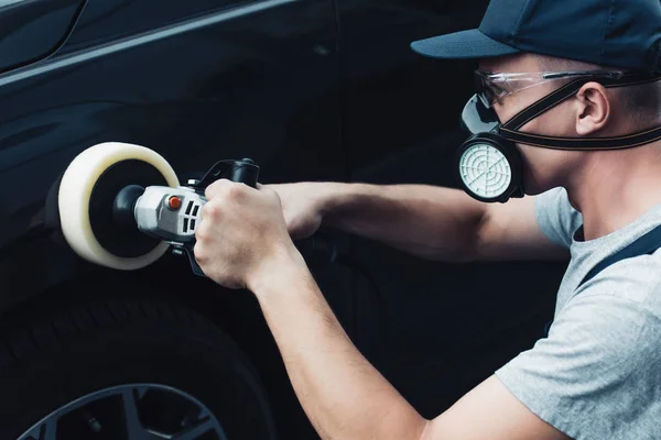 Limpiador de coches en el respirador y gafas de protección pulido coche con la máquina tampón - foto de stock