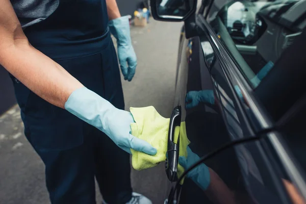 Обрезанный вид чистящего средства для автомобиля вытирая ручку двери автомобиля с тряпкой — стоковое фото
