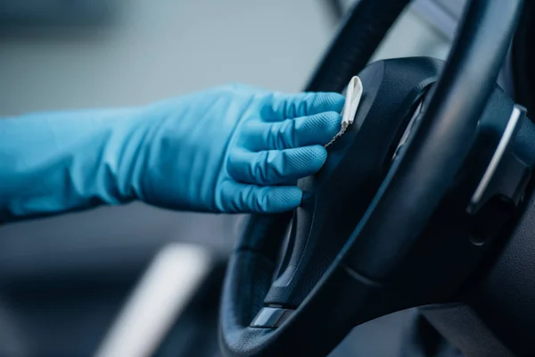 Cropped view of car cleaner in rubber glove wiping steering wheel — Stock Photo