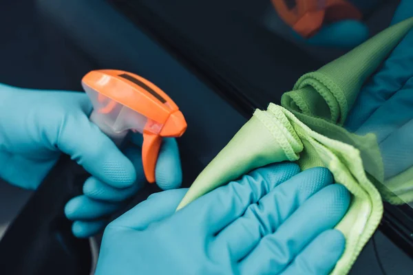 Vista cortada de carro limpador segurando garrafa de spray e limpando carro com pano — Fotografia de Stock