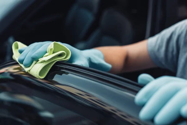 Partial view of car cleaner wiping black car door with rag — Stock Photo