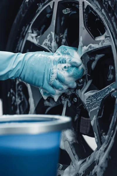 Partial view of car cleaner washing wheel with sponge and detergent — Stock Photo