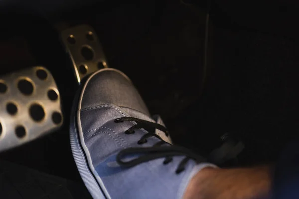 Vista parcial de la pierna masculina en zapatilla de deporte en el pedal de los frenos - foto de stock