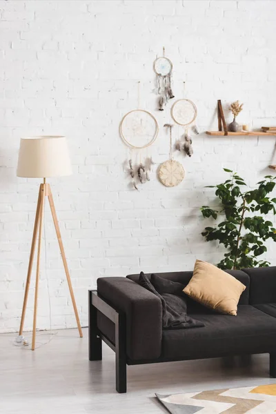 Intérieur du salon confortable avec canapé, lampe et attrape-rêves sur le mur blanc — Photo de stock