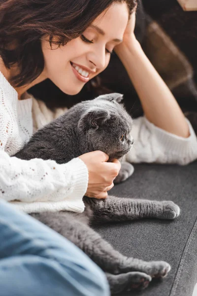 Belle fille heureuse couchée sur le canapé avec chat pliant écossais — Photo de stock