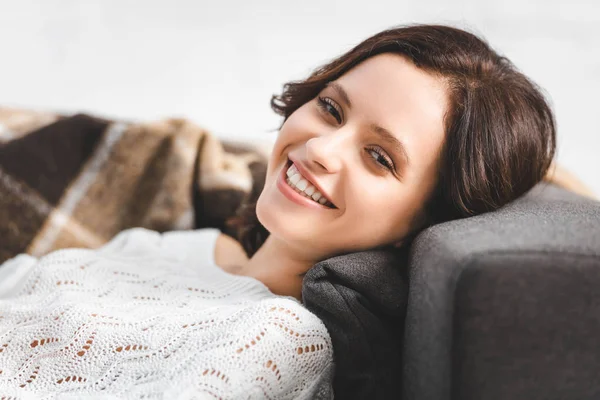 Belle fille heureuse couchée sur le canapé et regardant la caméra — Photo de stock