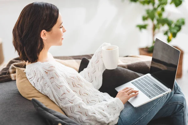 Menina bonita com xícara de chá usando laptop em casa aconchegante — Fotografia de Stock