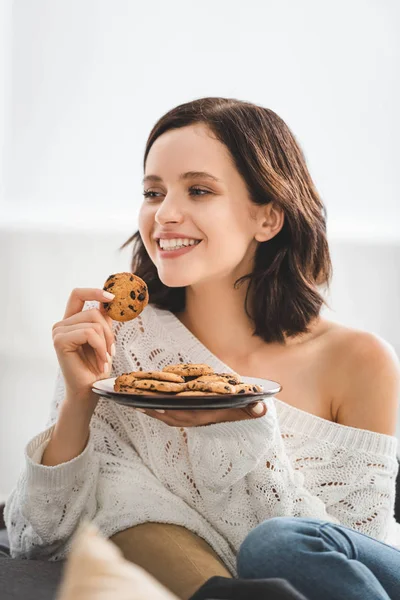 Красивая счастливая женщина ест печенье дома — стоковое фото